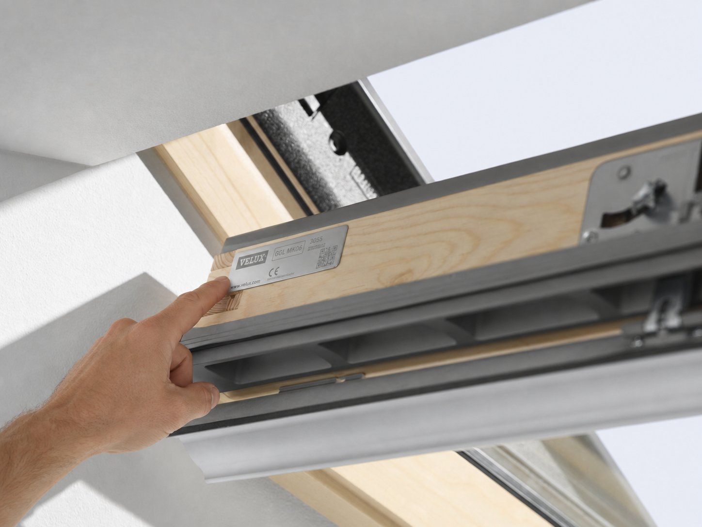 Hand zeigt auf das Typenschild eines geöffneten VELUX-Dachfensters