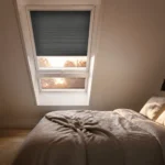 VELUX Hitzeschutz für Schlafzimmer Schlafzimmer unter dem Dach mit abgedunkeltem Dachfenster am Sommerabend