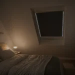 Verdunkelungsrollo mit Führungsschienen am Dachfenster im Schlafzimmer