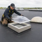 Dachhandwerker setzt eine neue transparente Oberschale auf den intakten Aufsatzkranz einer Lichtkuppel