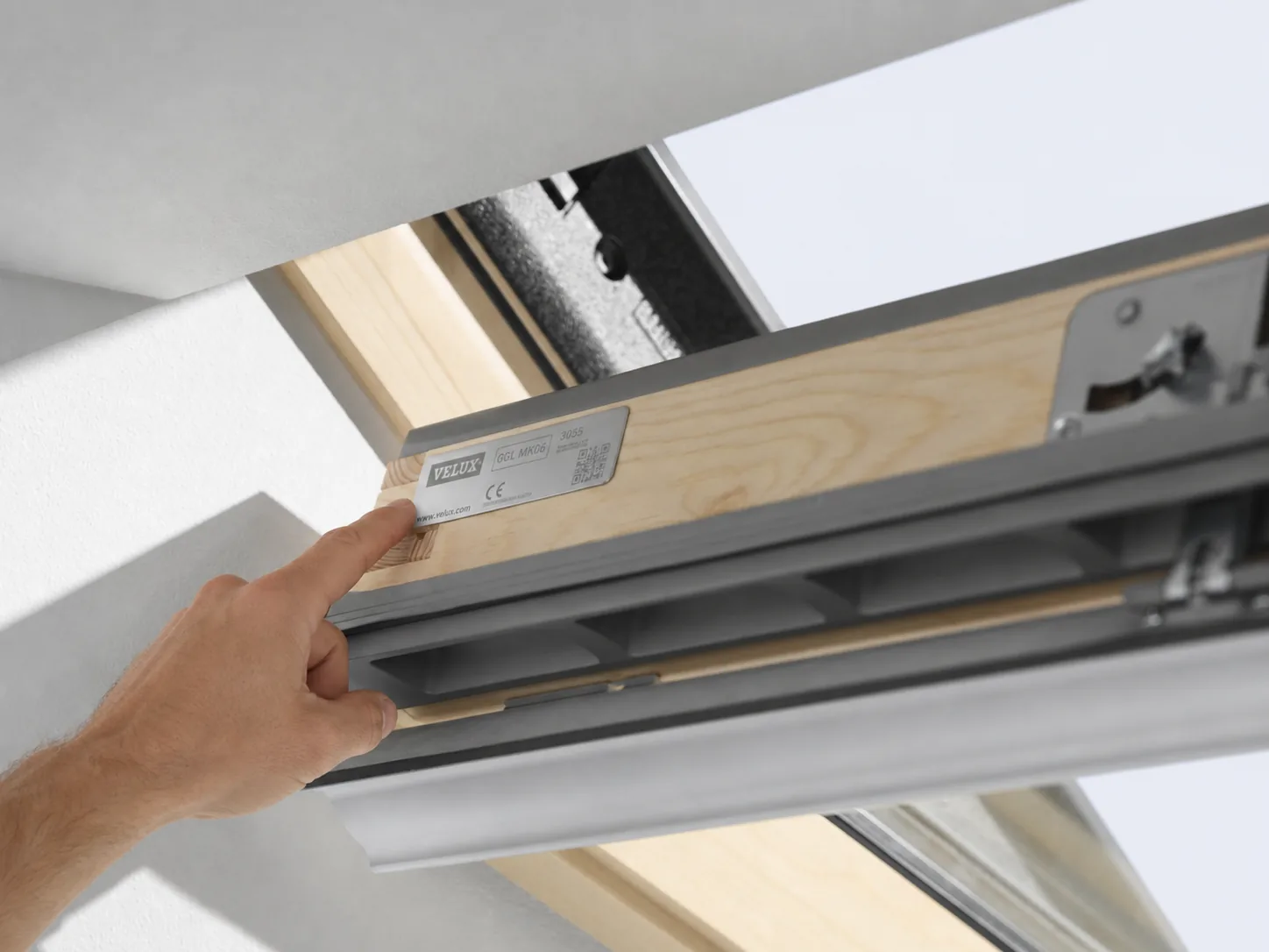 Hand zeigt auf das Typenschild eines geöffneten VELUX-Dachfensters
